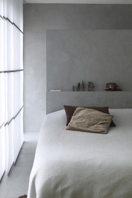 Chambre contemporaine avec mur en béton ciré, ambiance minimaliste et élégante.