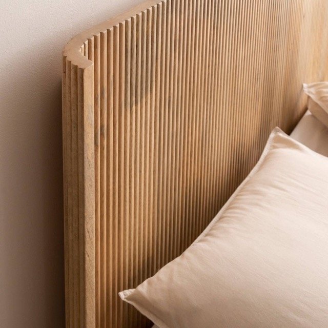 Chambre minimaliste avec tête de lit en bois strié naturel, décoration en tons neutres et épurés.