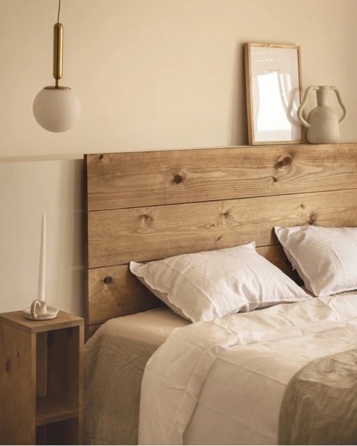 Chambre chaleureuse avec tête de lit en bois massif, décor minimaliste et ambiance naturelle.